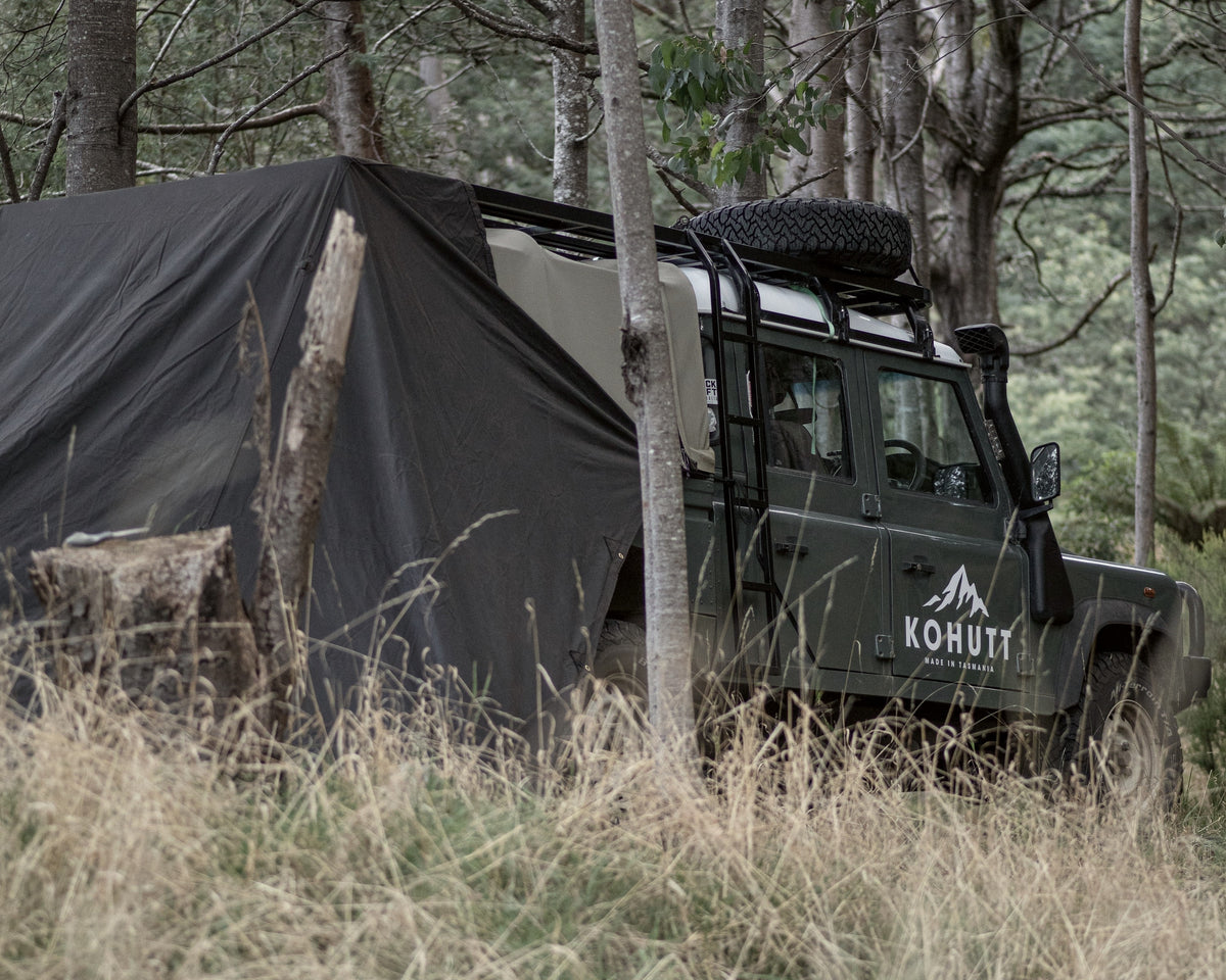 Oilskin field tarp shelter beside a Land Rover Defender